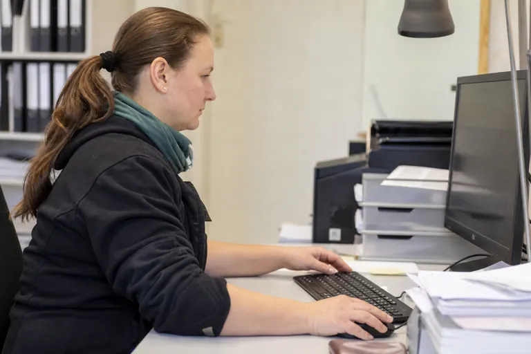 Handwerkerin richtet den digitalen Rechnungseingang am Büroarbeitsplatz ein