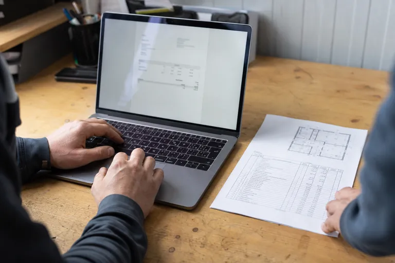 Lesbar dargestellte digitale Rechnung neben einem Aufmaß auf dem Bürotisch